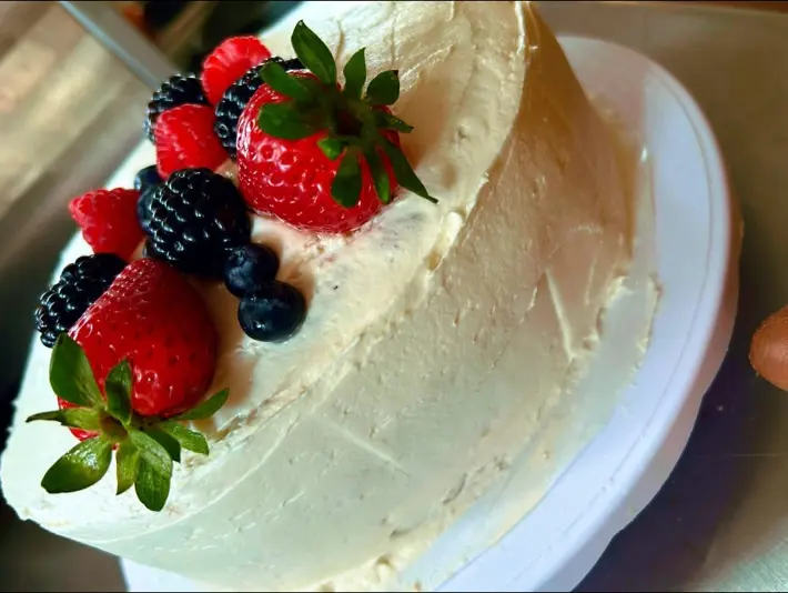 A frosted berry-topped cake from Mina's Kitchen