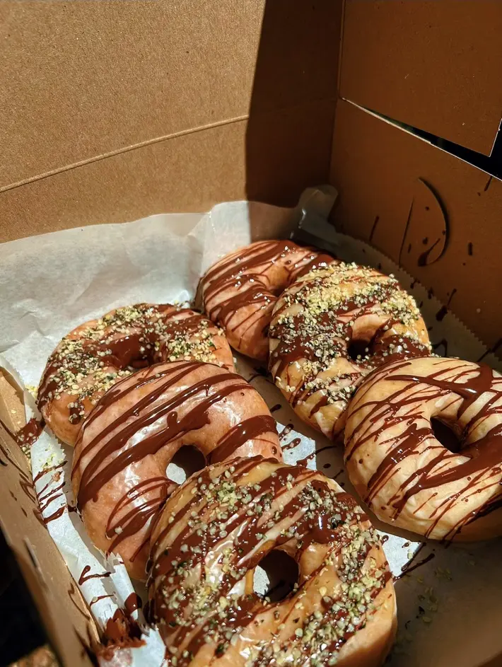 A full box of deluxe chocolate-drizzled plant-based donuts from Mina's Kitchen