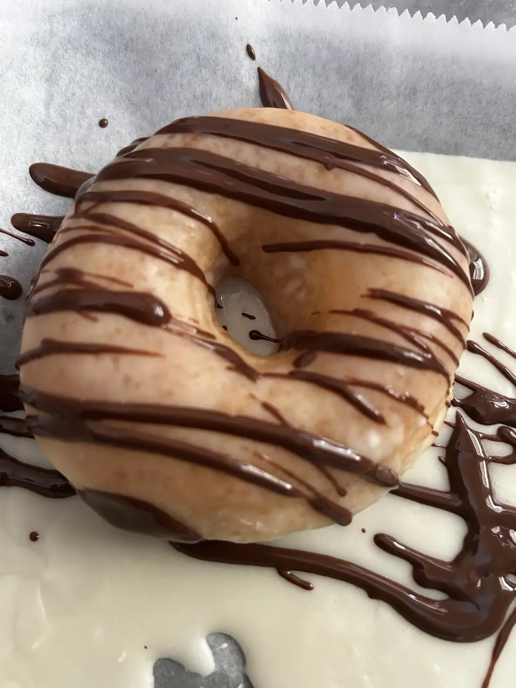A deluxe chocolate-drizzled plant-based donut from Mina's Kitchen