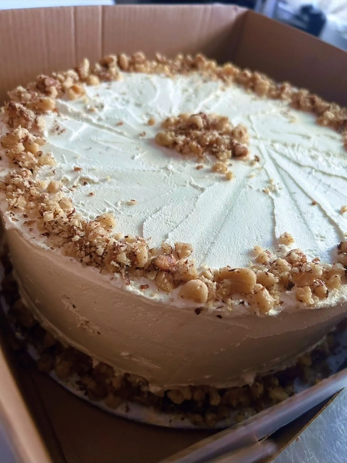 Mina’s Kitchen frosted cake decorated with chopped nuts